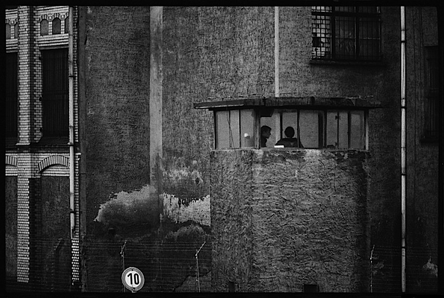 Photographie noir et blanc d'une tour de garde en pierre devant un immeuble lui-même en pierre