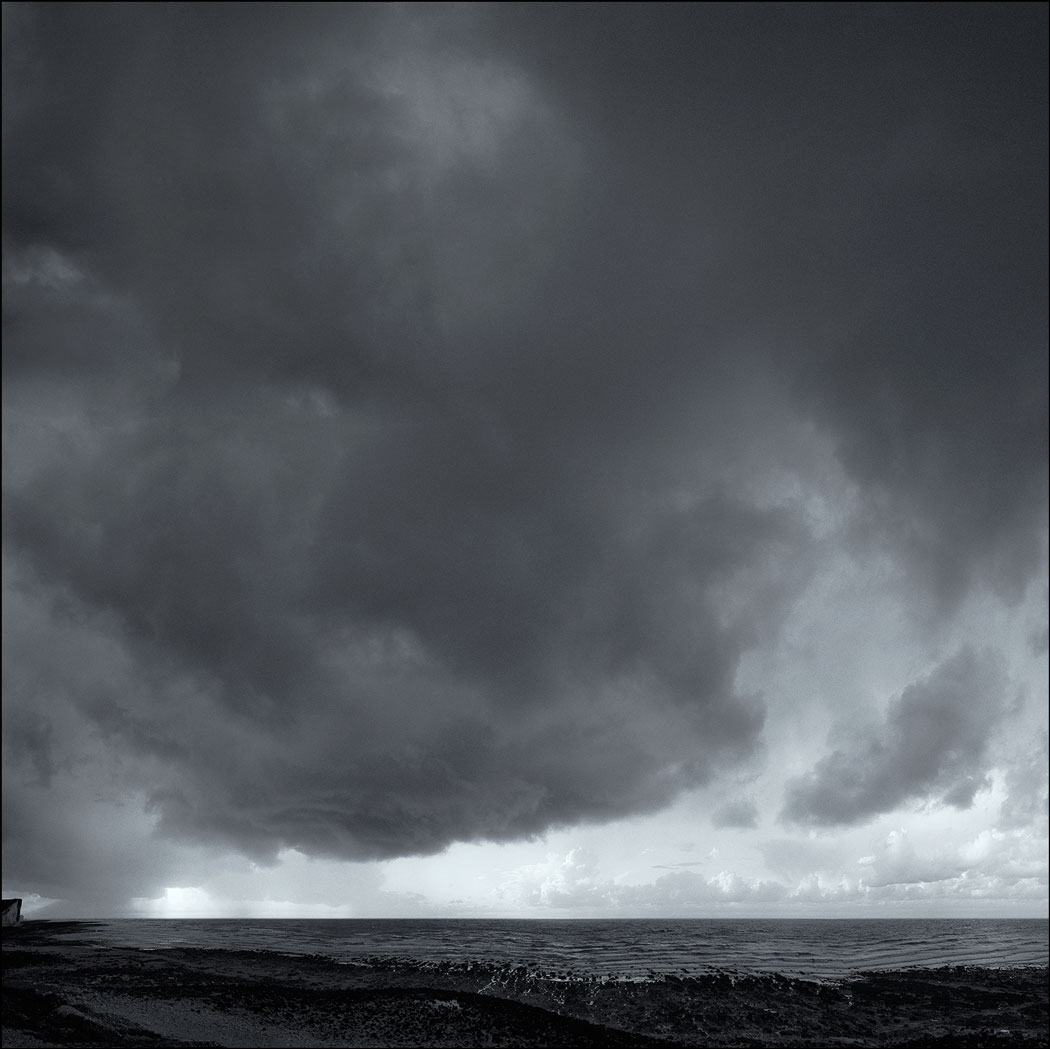 Photographie numérique d'un ciel nuageux et menançant avec la mer et un bout de plage